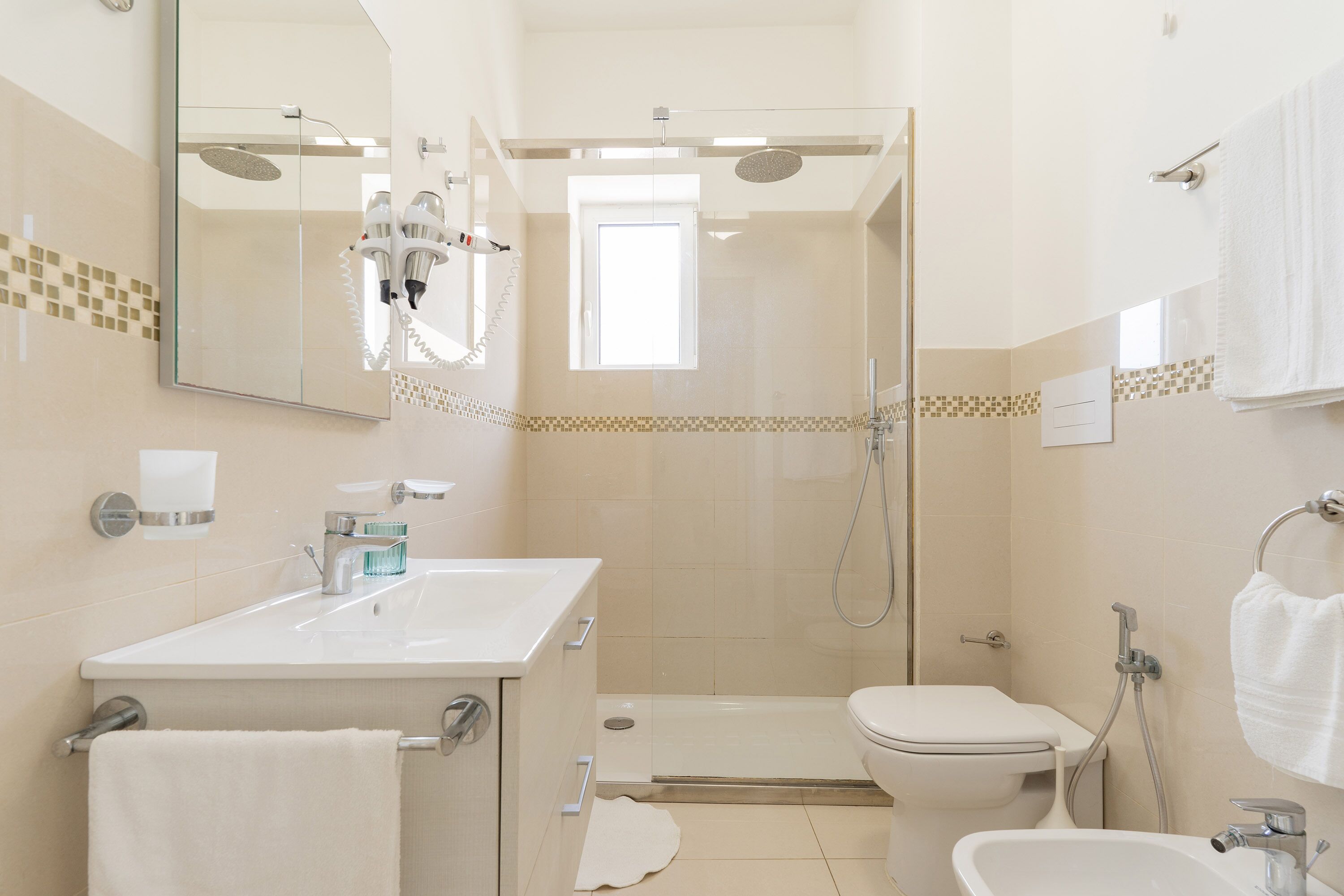 Un bagno moderno con cabina doccia in vetro, lavandino bianco e water.