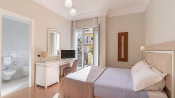 Camera d'albergo con un letto, una scrivania, una televisione, un bagno con bidet e un balcone con vista sugli edifici.