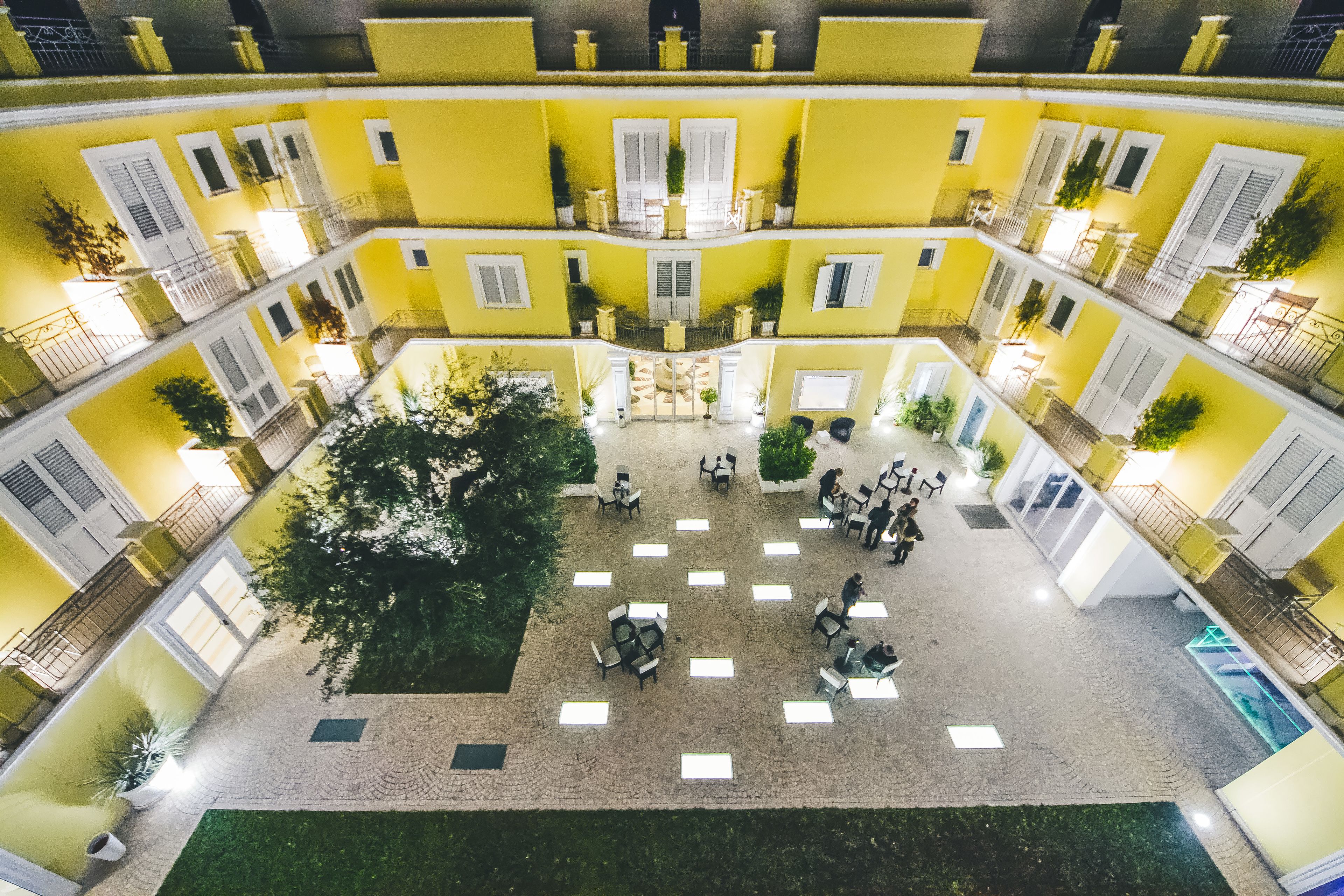 Une cour avec des murs jaunes, de nombreux balcons et des espaces aménagés pour s’asseoir à l’extérieur.