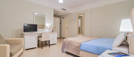 Une chambre d’hôtel comprenant un lit, un bureau avec un ordinateur, une chaise, un canapé et une table de chevet avec une lampe.
