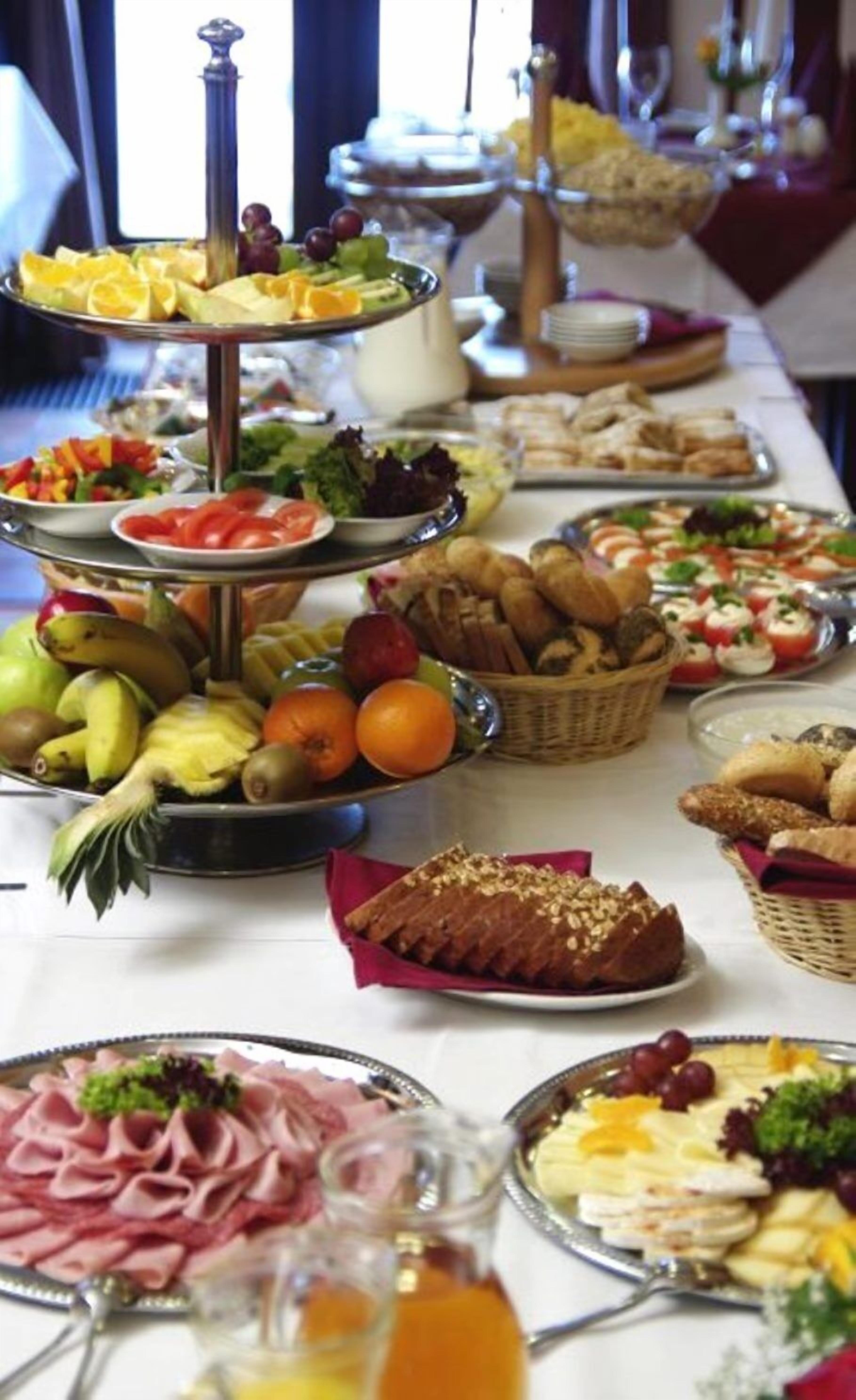 A buffet table with various food items including fruits, vegetables, breads, and cheeses.