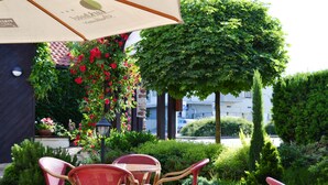 An outdoor seating area with wicker chairs and a table under a canopy. - Park Hotel Pruhonice (Pruhonice)