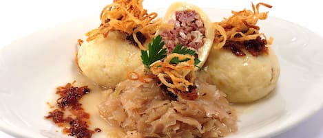 Un plato de dumplings con cebollas fritas como guarnición y col fermentada al lado.