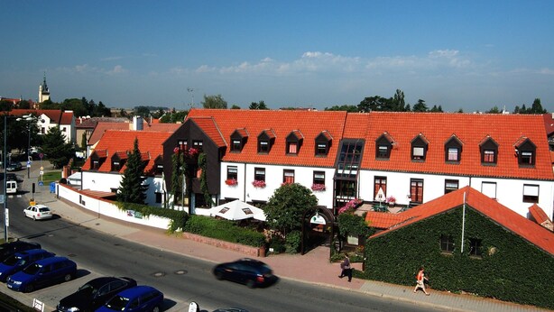 A building with a red-tiled roof, multiple windows, and a white facade. - Park Hotel Pruhonice (Pruhonice)