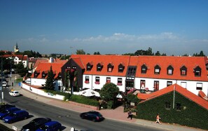 A building with a red-tiled roof, multiple windows, and a white facade. - Park Hotel Pruhonice (Pruhonice)