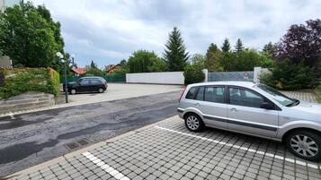A residential street with parked cars and a white building with a satellite dish.