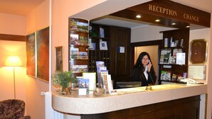 A reception desk with a 'RECEPTION CHANGE' sign, a mirror, a lamp, a plant, and a bulletin board with various notices. - Park Hotel Pruhonice (Pruhonice)