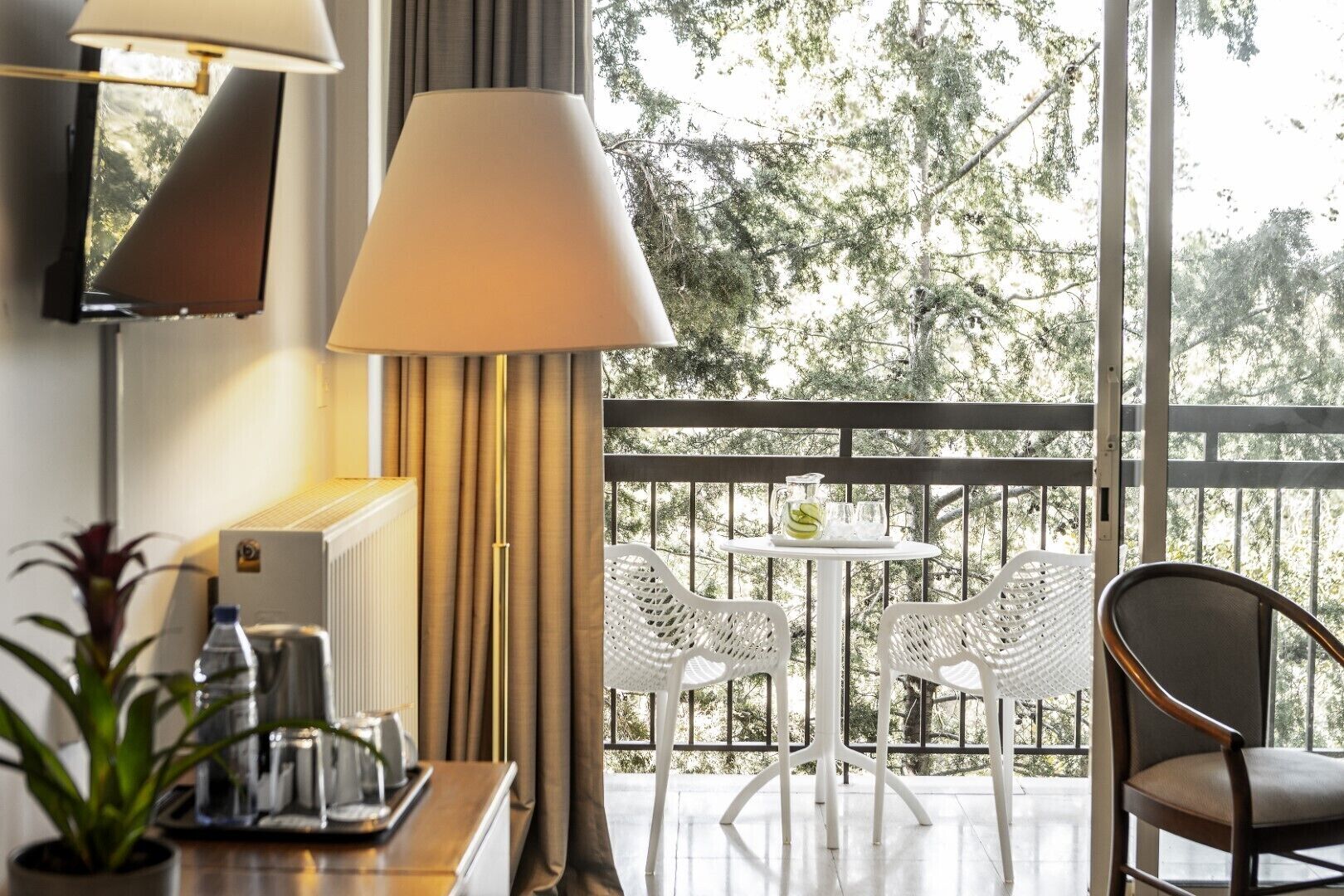 A balcony with a table and chairs, a radiator, and a lamp.