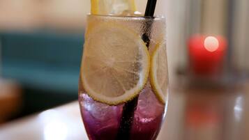 A glass with a dark-colored beverage, lemon slices, and a straw on a wooden table.