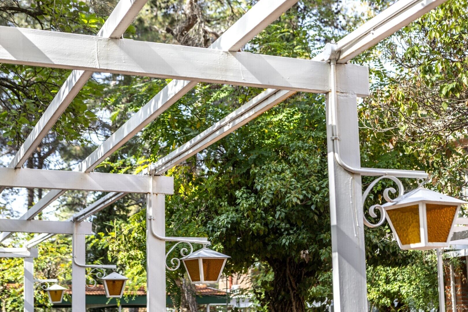 Una estructura de pérgola de metal blanco con lámparas de estilo farol.
