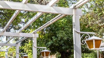 Una estructura de pérgola de metal blanco con lámparas de estilo farol.