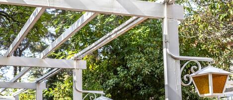 Una estructura de pérgola de metal blanco con lámparas de estilo farol.
