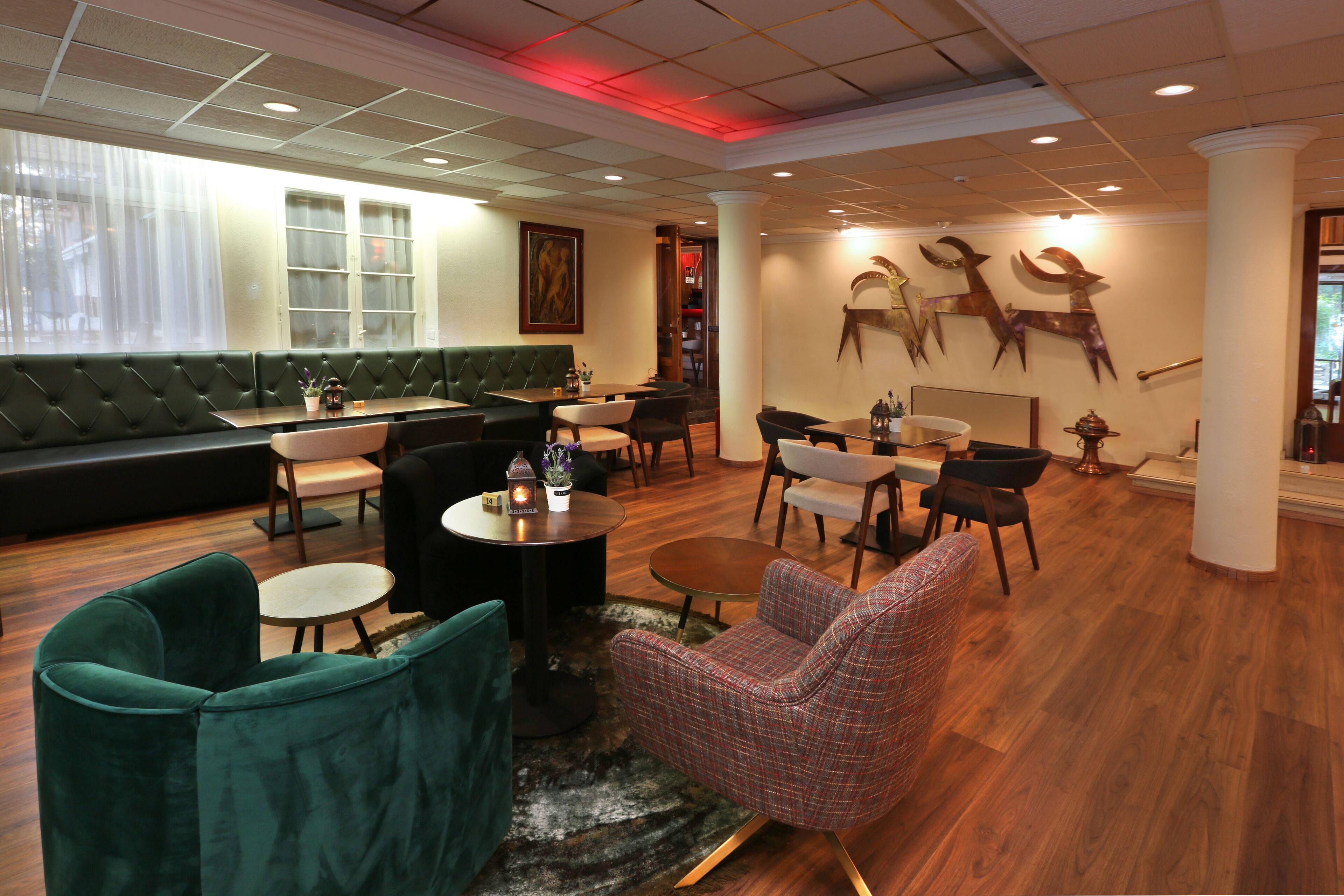 A modern lounge area with a green sofa, multiple seating options, and a decorative wall with animal sculptures.
