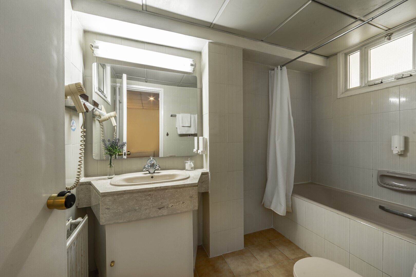 A bathroom with a sink, mirror, shower, and toilet.