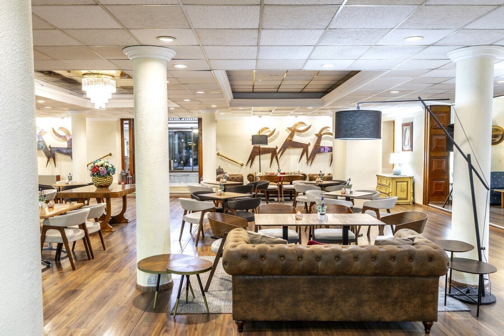A spacious dining area with high ceilings, wooden flooring, and a mix of tables and chairs.