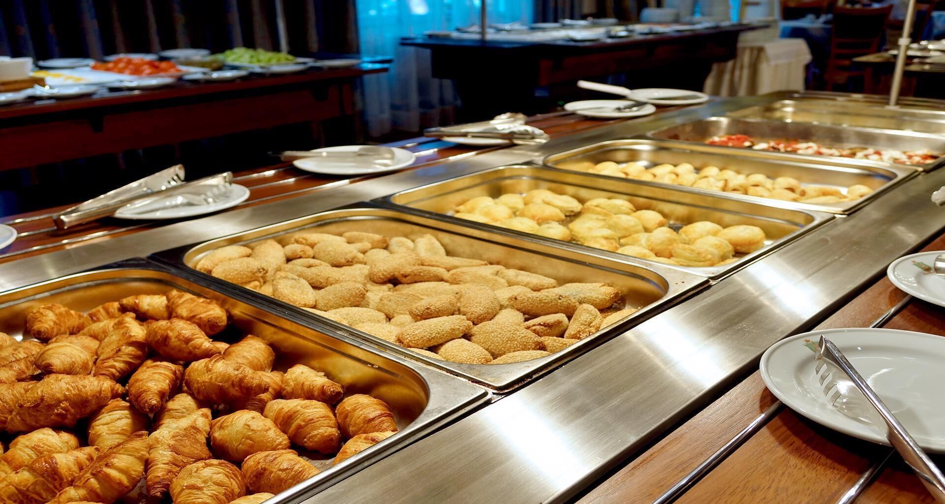 Een buffet met diverse gerechten, waaronder croissants en andere gebakjes.