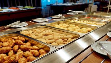 Un bufé con diversas opciones de comida, incluyendo cruasanes y otras vieneserías.