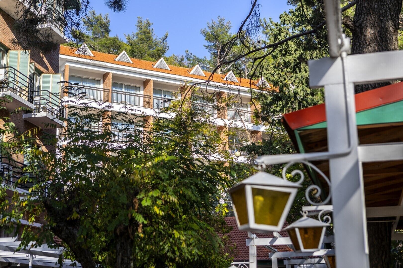 A multi-story building with balconies, surrounded by trees and greenery.