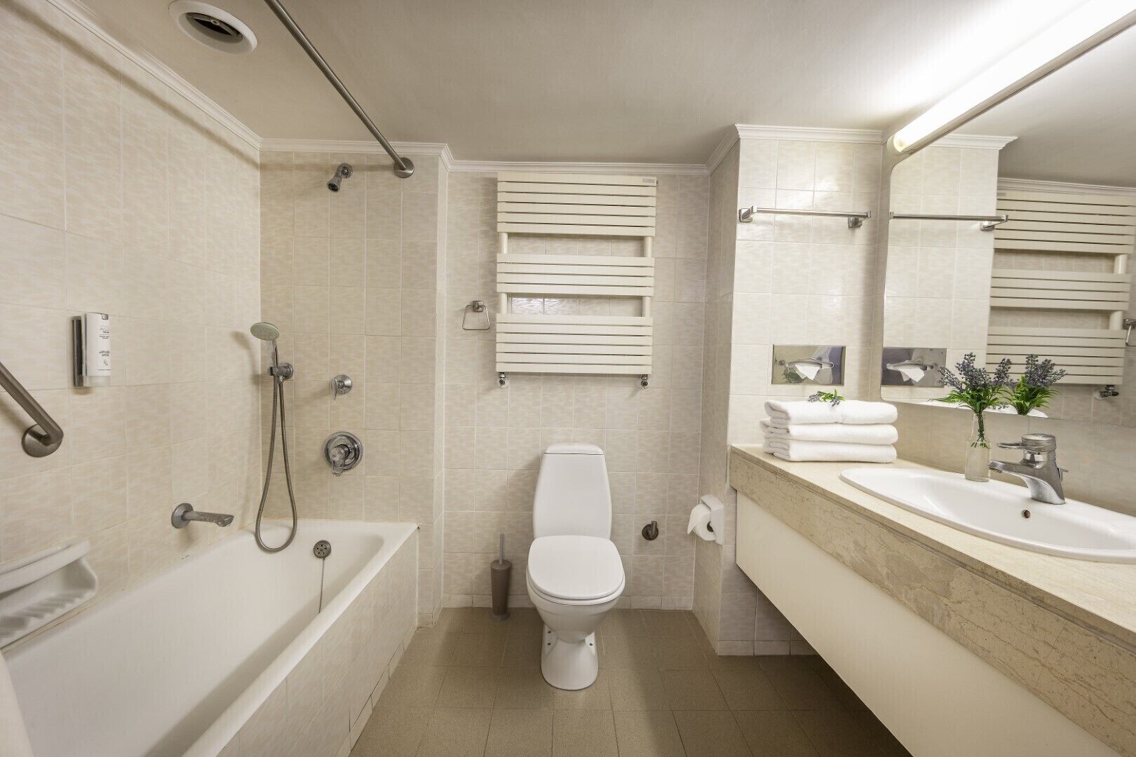 A modern bathroom with a bathtub, shower, toilet, and vanity with a sink and mirror.