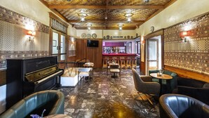 A bar area with a piano, seating, and a patterned wall. - Forest Park Hotel (Platres)