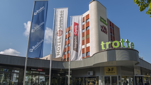 A hotel with multiple flags, including 'HOTEL SURSUEE' and 'trotte'.