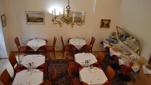 A dining area with multiple tables and chairs, a chandelier, and framed pictures on the walls. - Hotel Pension Walzerstadt (Vienna)