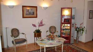 A room with two chairs, a table with magazines, a bookshelf, and a chandelier. - Hotel Pension Walzerstadt (Vienna)