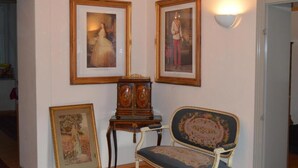 A room with framed pictures on the wall, a wooden cabinet, and a vintage chair. - Hotel Pension Walzerstadt (Vienna)