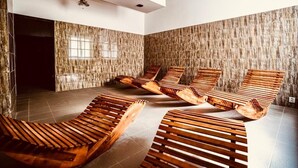 A spa room with wooden loungers, a tiled floor, and a stone wall. - Interhotel America (Pisek)