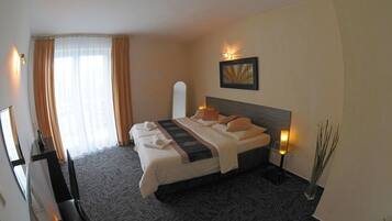 A hotel room with a large bed, a bedside table with a lamp, a mirror, and a painting on the wall.