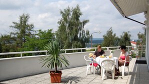 A terrace with a table and chairs, a potted plant, and a view of trees and buildings. - Interhotel America (Pisek)