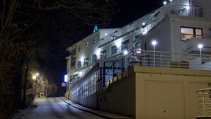 A multi-story building with a staircase leading to the upper floors, a snow-covered ground, and a street with streetlights. - Interhotel America (Pisek)