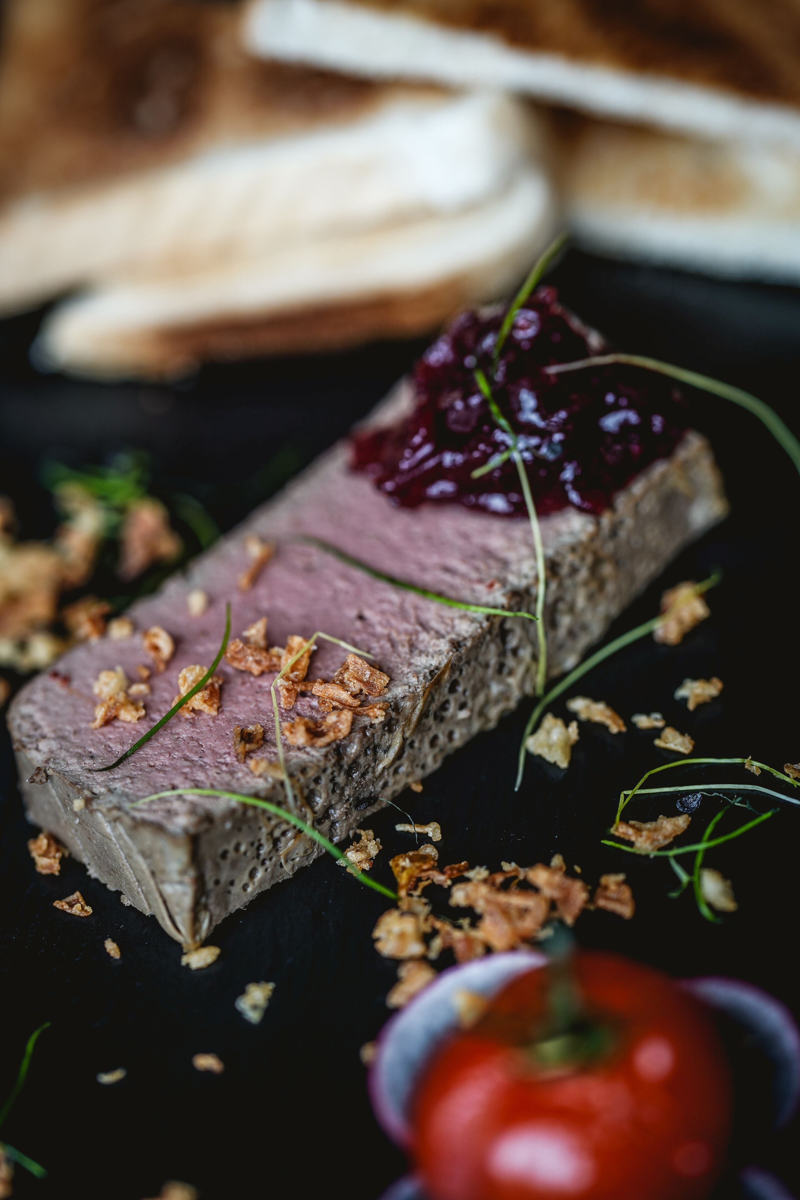 En närbild av en maträtt med en krämig konsistens, garnerad med gröna blad och smulade toppingar, placerad på en mörk yta.
