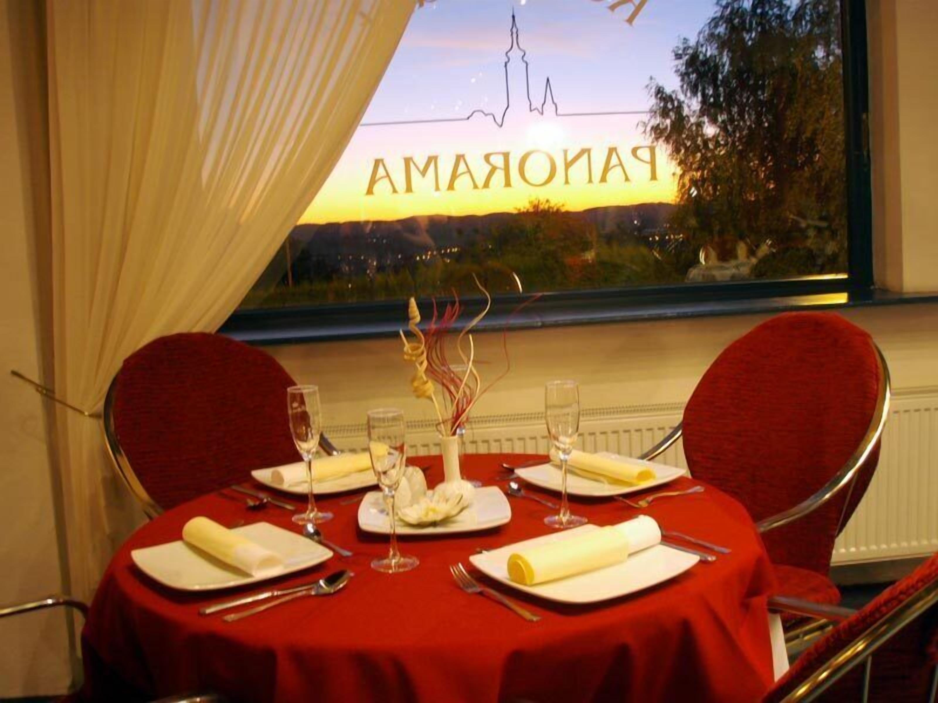 Mesa para dos personas dispuesta con mantel rojo, servilletas blancas y copas de vino.