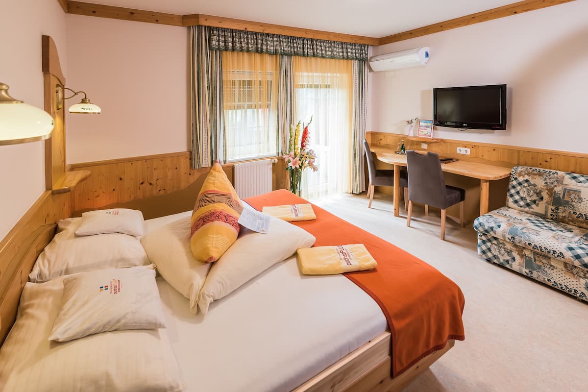 Ein Hotelzimmer mit Bett, Schreibtisch, Fernseher und einer Couch.