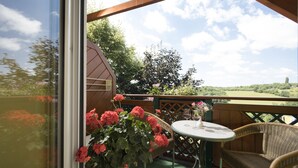 Un balcon agrémenté de meubles en osier, d’une table et d’un vase rempli de fleurs.