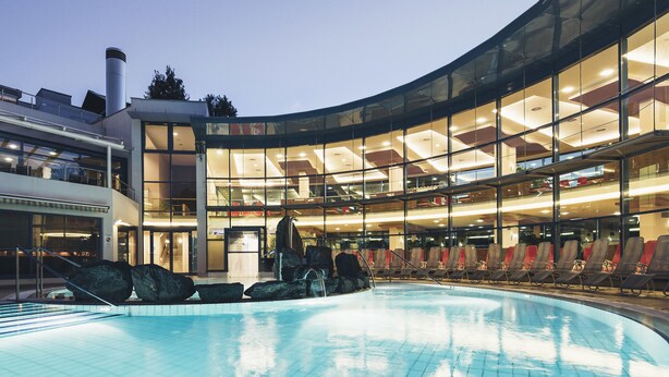 Un hôtel moderne doté d’une piscine, d’une façade en verre et d’une terrasse sur le toit.