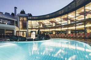 A modern hotel with a swimming pool, a glass facade, and a rooftop terrace. - Thermenhof PuchasPLUS Loipersdorf (Jennersdorf)