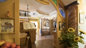 Un intérieur chaleureux avec un comptoir en bois, une enseigne indiquant « salle de petit-déjeuner », et un grand vase rempli de tournesols.