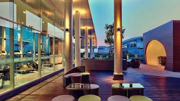 A modern outdoor seating area with wicker furniture and glass walls.