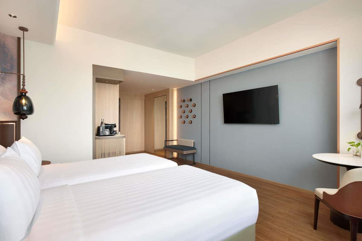 Habitación de hotel con una cama grande, un televisor en la pared, una mesita pequeña y una silla.