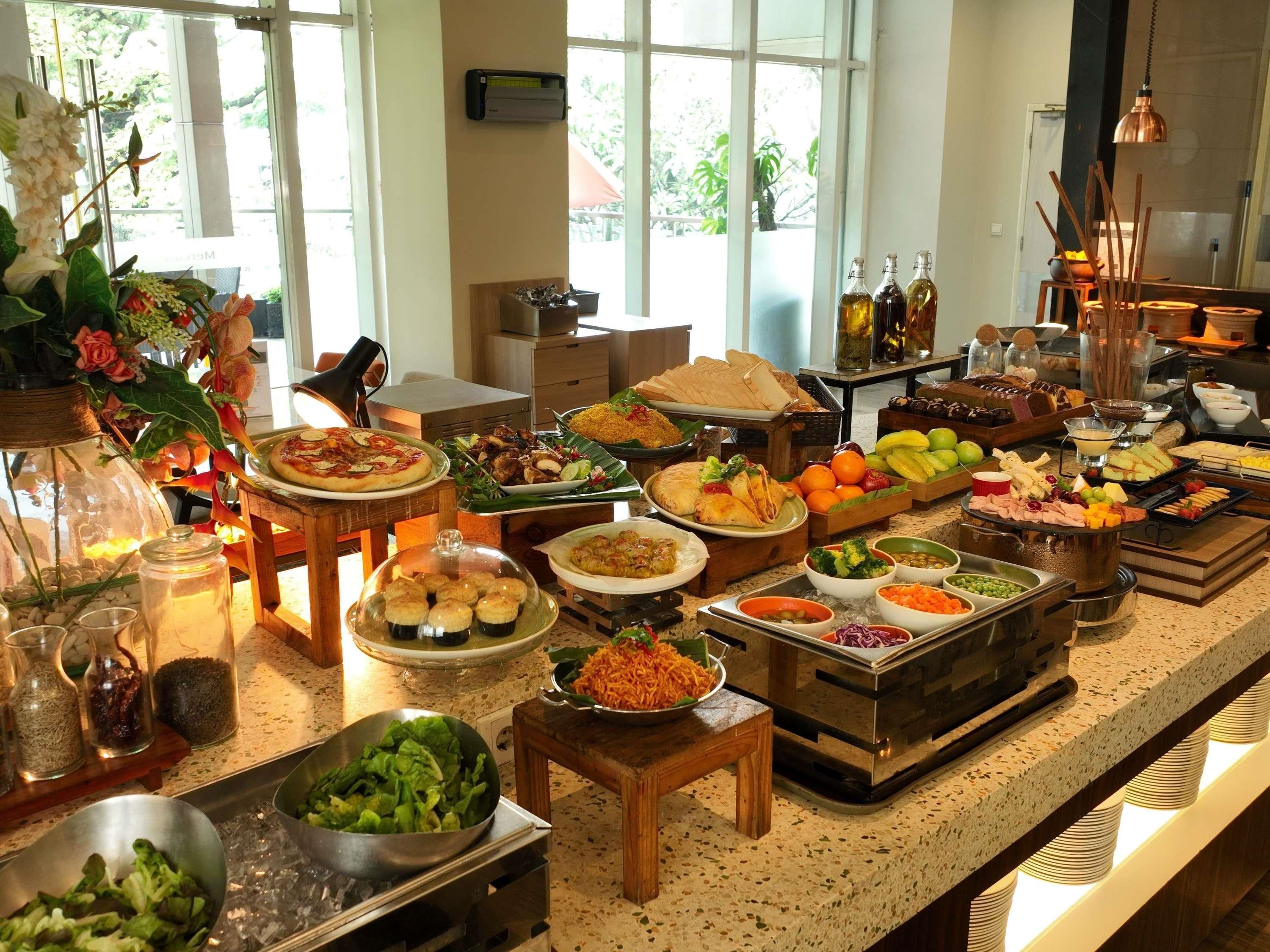 A buffet with various food items and beverages, a coffee station, and a decorative plant arrangement.