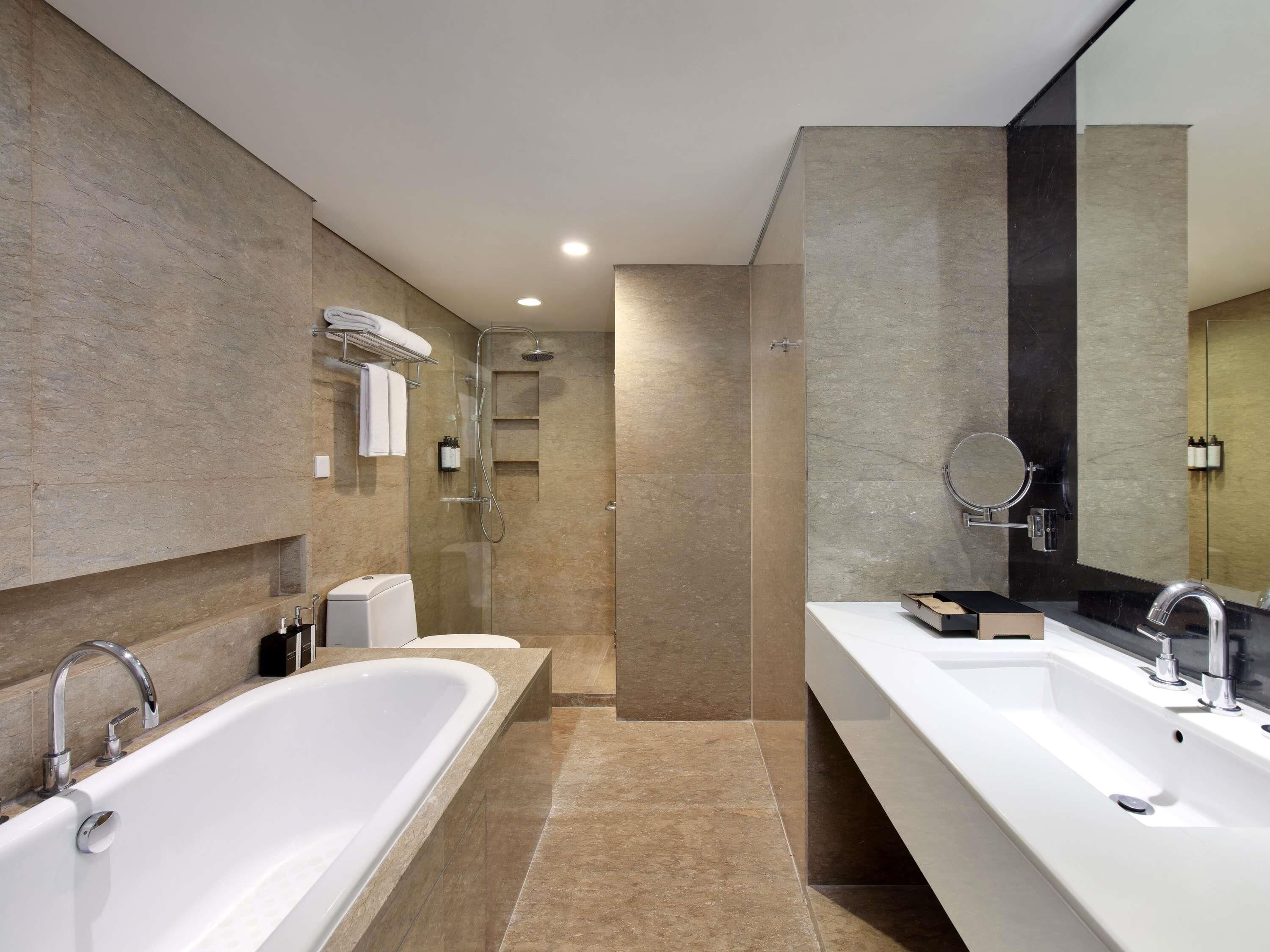 A modern bathroom with a large bathtub, two sinks, a shower, and a mirror.