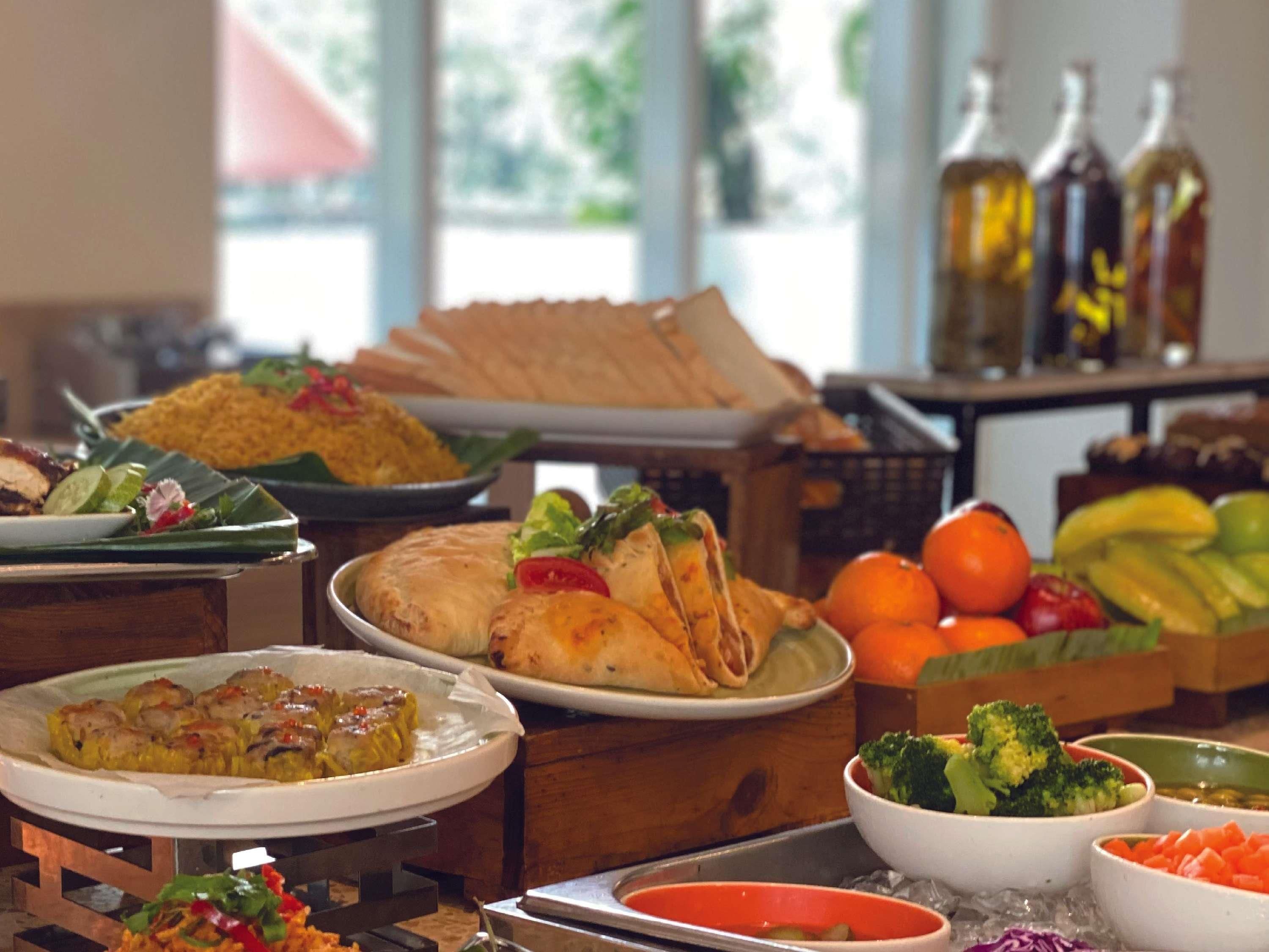 A buffet with various dishes, including a plate of rolled meat, a bowl of rice, and a tray of vegetables.