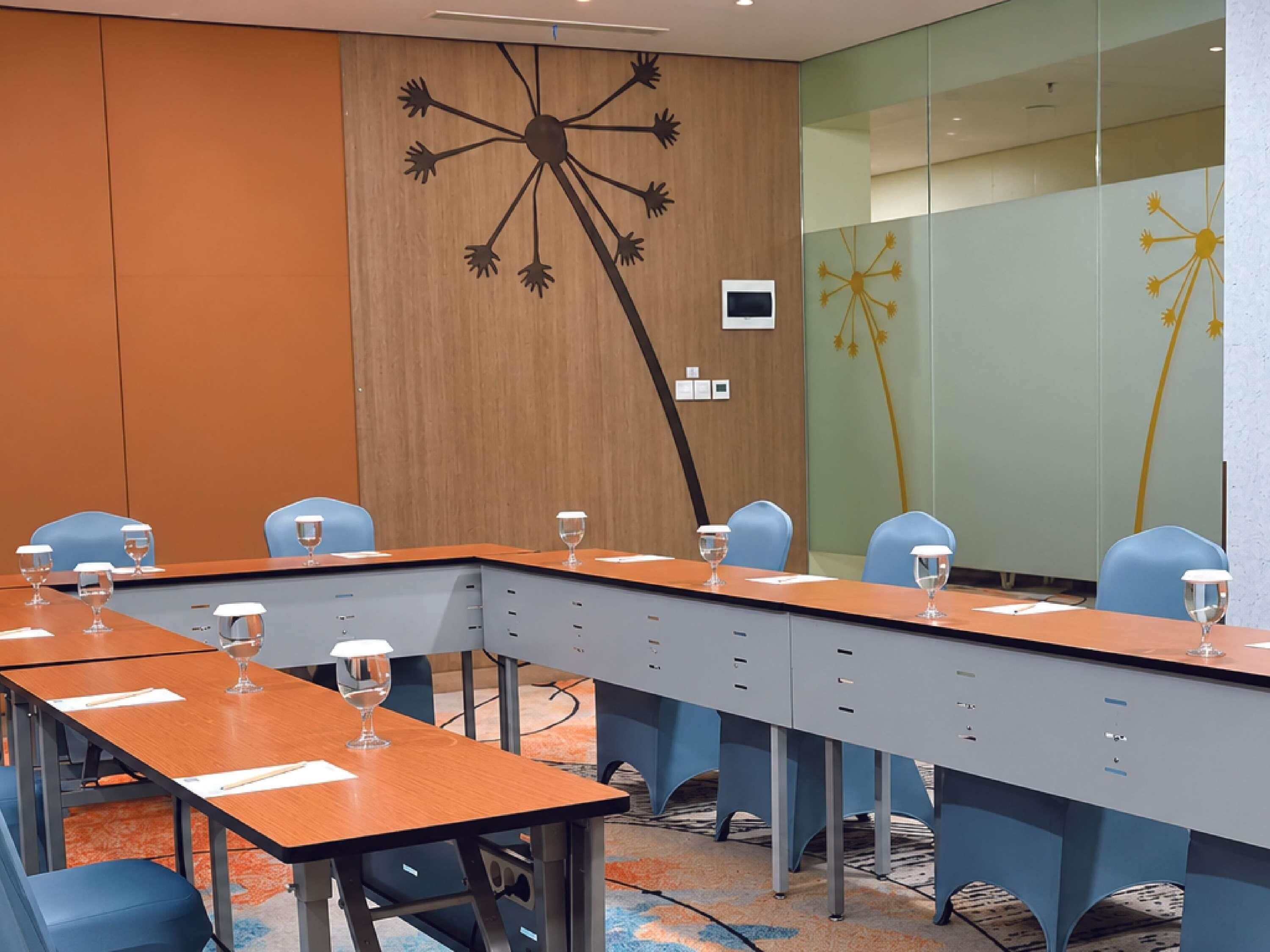 A conference room with a long table, chairs, and a wall with a dandelion design.
