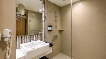 A modern bathroom with a white sink, a large mirror, a shower, and a glass-enclosed shower area.