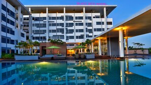 Un hotel moderno con piscina, zona de estar al aire libre y una entrada bien iluminada.