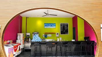 Terraza de piscina Manzil con zona de bar, máquina de helados y cartel de menú.