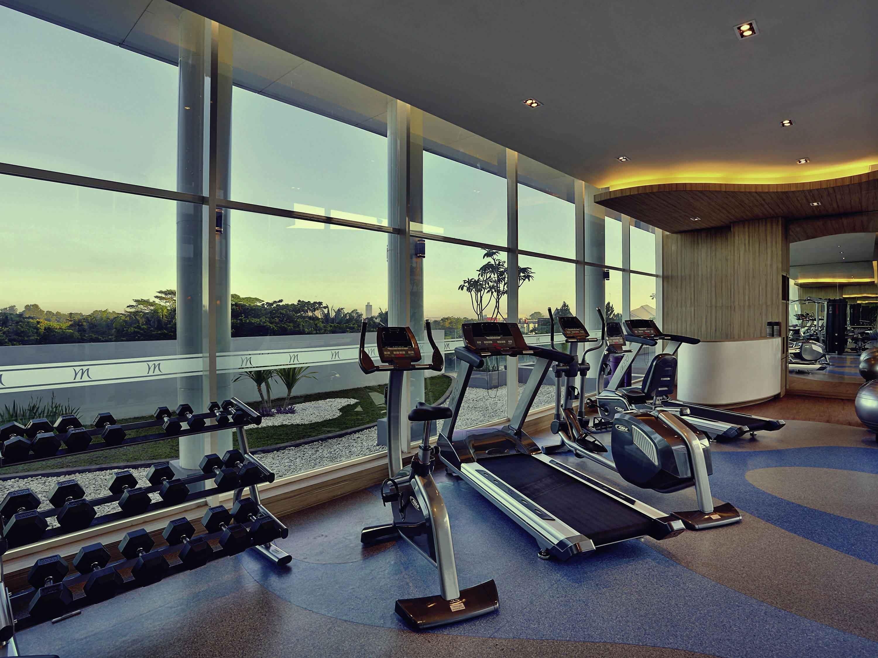 Un gimnasio con cintas de correr, mancuernas y pelotas de ejercicio.