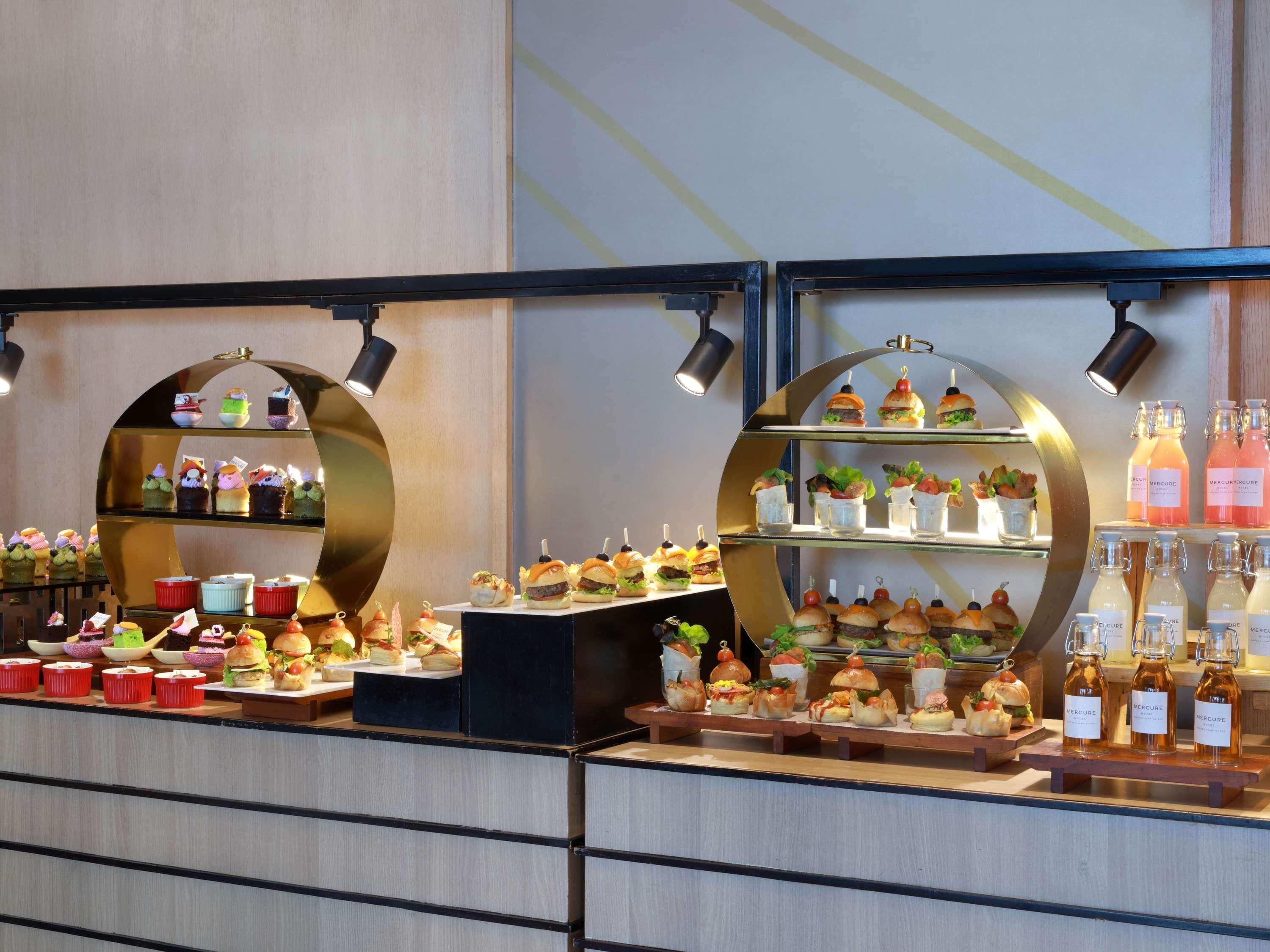 Uma área de buffet com diversas opções de comida, incluindo cupcakes, sanduíches e bebidas.